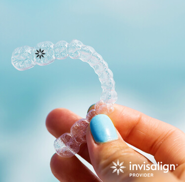 An Invisalign clear aligner tray being held by a woman